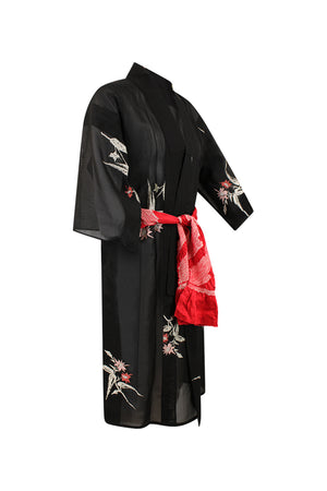 Three quarter view ghost image of Kiku modified black summer silk kimono on a white background. The robe has pink, red floral bundles beautifully scattered on the Kimono and is tied with a red sash.